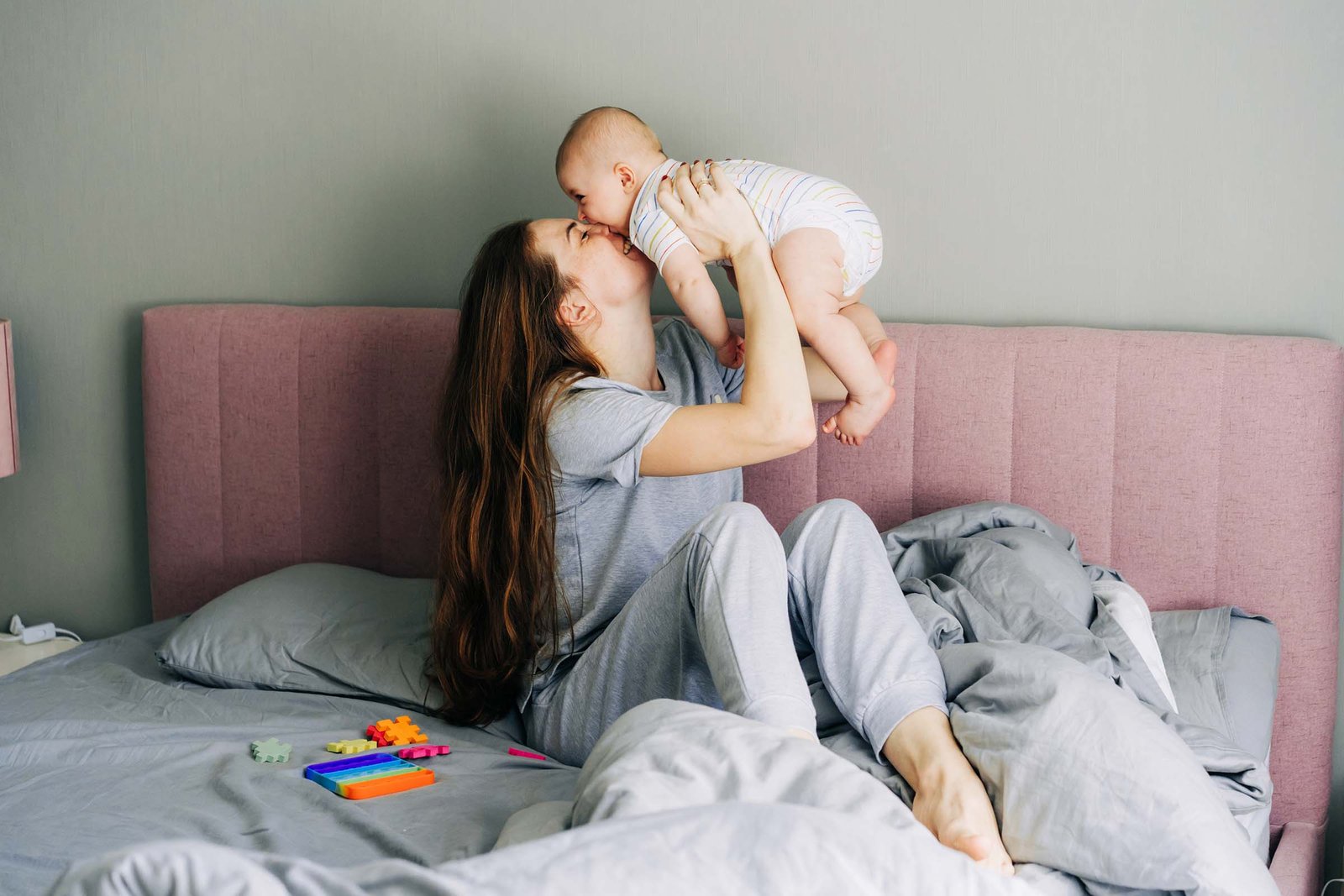 mom holds and kisses the baby caring for the baby LCCU6KC