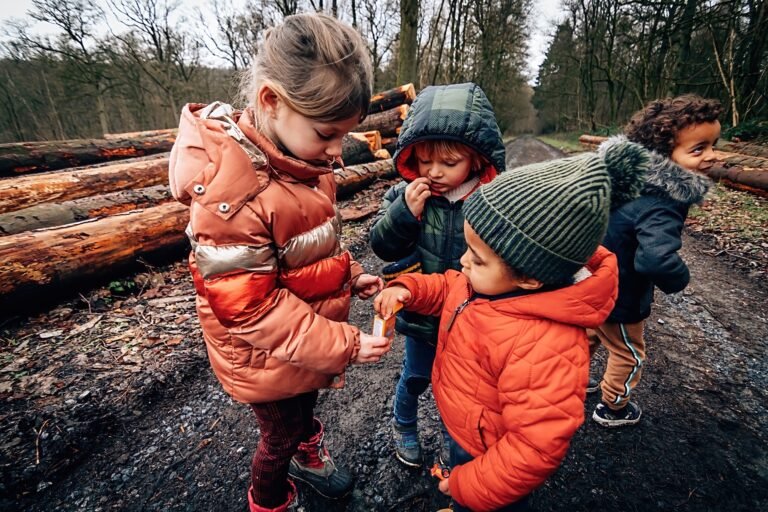 friends children share candy - mixed race siblings outdoors in wood
